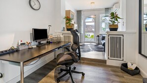 Een moderne kantoorruimte met een bureau, computer, stoel en een klok aan de muur.