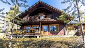 A wooden cabin with a balcony, surrounded by trees.