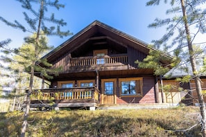 Une cabane en bois dotĂ©e dâun balcon, entourĂ©e dâarbres.