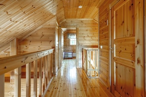 Un intérieur en bois avec un plafond en pente, un couloir central et des murs en bois.