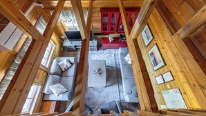 A wooden cabin interior with a sofa, a coffee table, and a red cabinet.