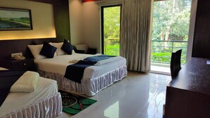 Habitación de hotel con cama, mesitas de noche, un escritorio y vistas al verdor.