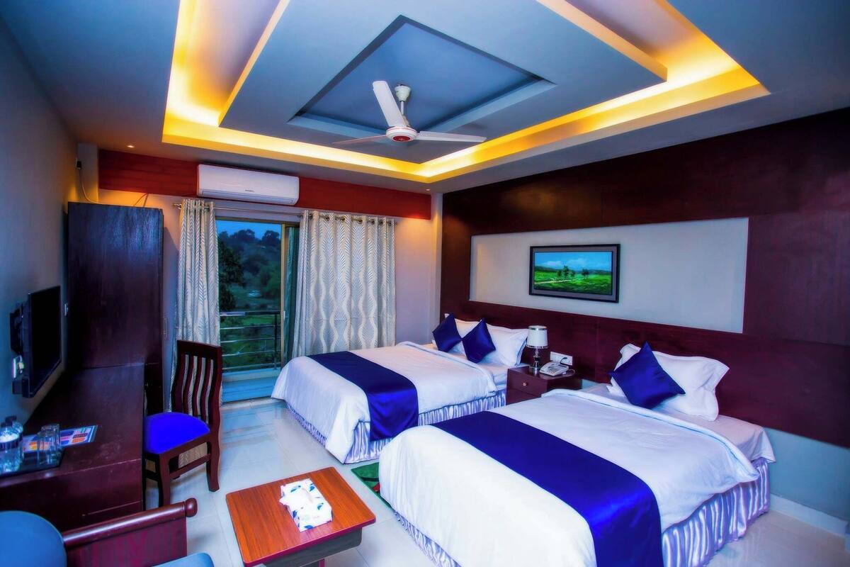 Una habitación de hotel con dos camas, televisión, escritorio y silla.