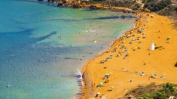 A beach with clear water, a sandy shore, and a lighthouse.