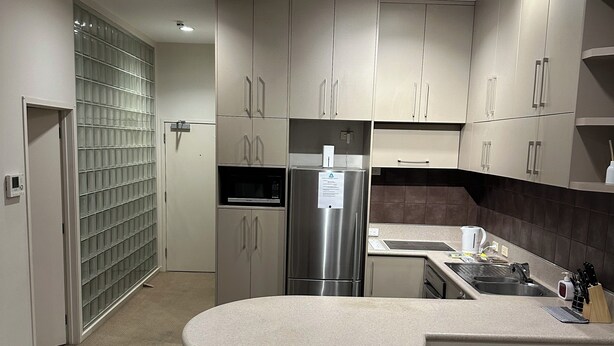 Una cocina moderna con una isla central, electrodomésticos de acero inoxidable y una mesa de comedor de vidrio.