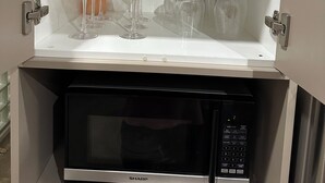Una cocina con microondas y un armario con copas de vino.