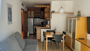 A compact living space with a sofa, dining table, chairs, a kitchen area with appliances, and a TV. - In the heart of Salou, Senator Building (Salou)