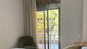 A bedroom with a bed, pillows, a chair, a lamp, and a view of an outdoor balcony. - In the heart of Salou, Senator Building (Salou)