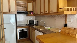 A compact kitchen with a refrigerator, microwave, toaster, sink, and wooden cabinets. - In the heart of Salou, Senator Building (Salou)