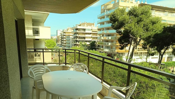 A balcony with a round table and four chairs, overlooking a residential area with multi-story buildings and greenery. - In the heart of Salou, Senator Building (Salou)