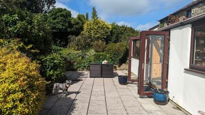 A paved patio with a seating area, a small table with a teapot, and a wooden bench. - Trehaverock Cottage (Port Isaac)