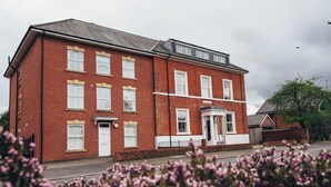 A red brick building with multiple windows and a small porch.