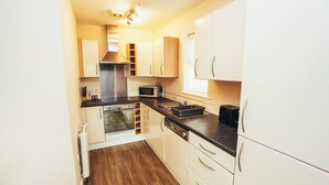 A compact kitchen with white cabinets, a microwave, a toaster, and a built-in oven.