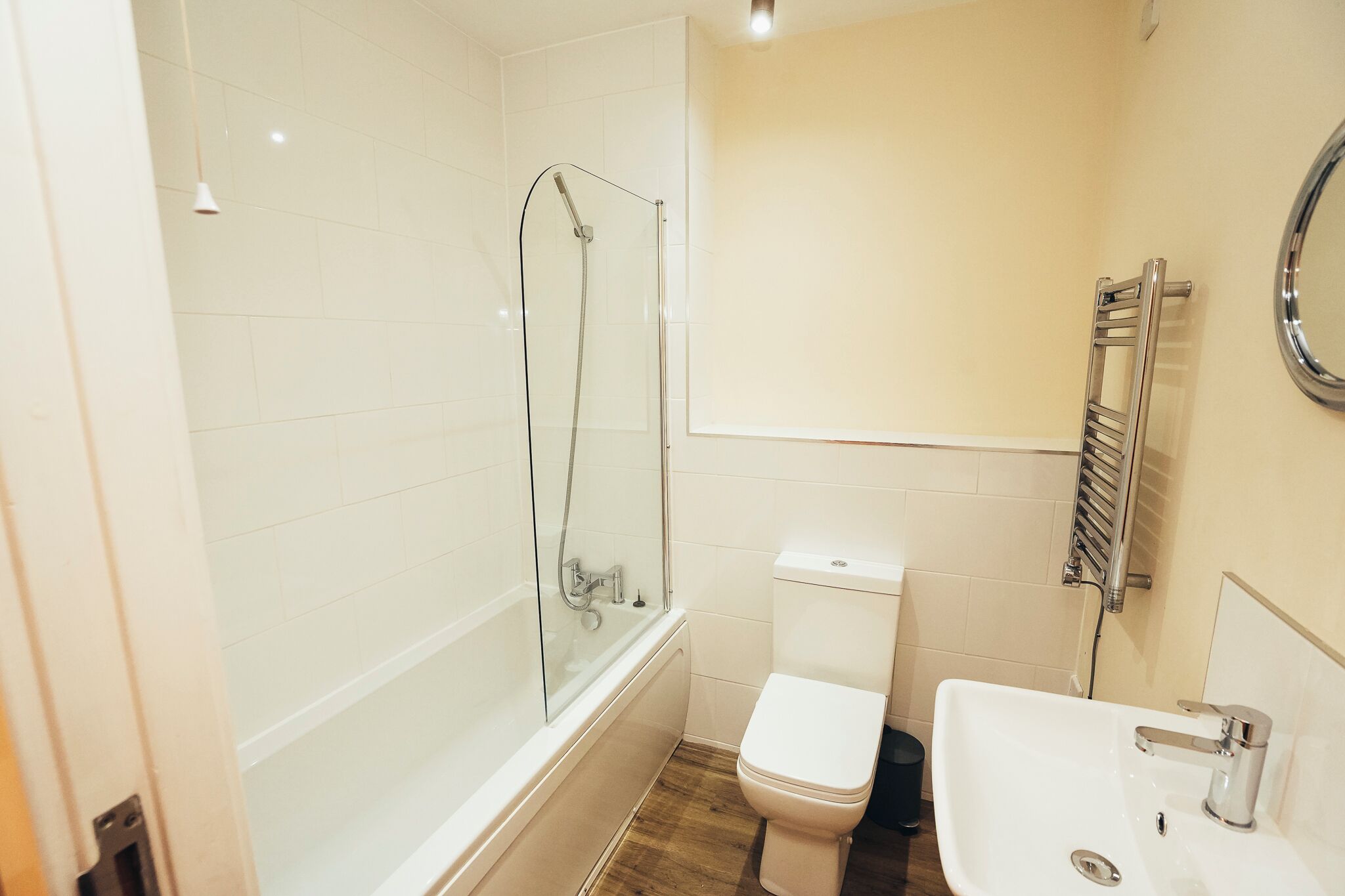 Un baño con ducha de mampara de vidrio, inodoro blanco y lavabo con espejo.