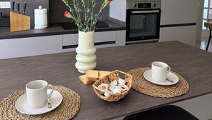 Een moderne keuken met houten kastjes, een magnetron en een vaas met bloemen op het aanrecht.