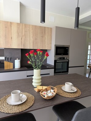 A modern kitchen with wooden cabinets, a microwave, and a vase with flowers on the counter. - Frames of green - Cortona (Toscana)