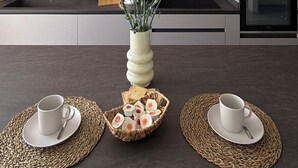 Een moderne keuken met hanglampen, een centraal eiland met een bloevas en een inbouwoven.
