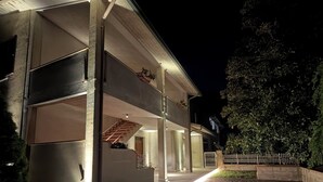 Een modern huis met een overdekte veranda, een trap en een goed verlichte entree.