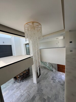 Un interior moderno con una araña colgante, una escalera y un comedor.