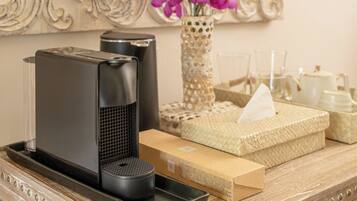 A bathroom vanity with a mirror, a vase of flowers, a coffee maker, and a tissue box.
