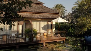 A house with a wooden deck, a covered seating area, and a pond with lily pads. - Serene Maerim Villa (Mae Rim)