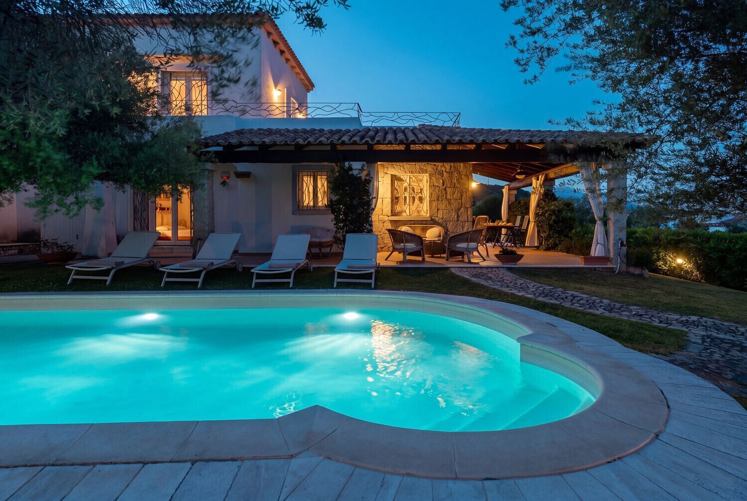 A house with a swimming pool, lounge chairs, and a patio area.