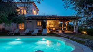 Uma casa com piscina, espreguiçadeiras e um espaço de pátio.
