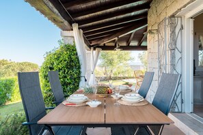 An outdoor dining area with a wooden table, chairs, and a view of the garden. - Villa Luciva by Klodge - Pool escape in San Teodoro (San Teodoro)
