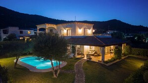 Uma villa com piscina, área de estar externa e varanda coberta.