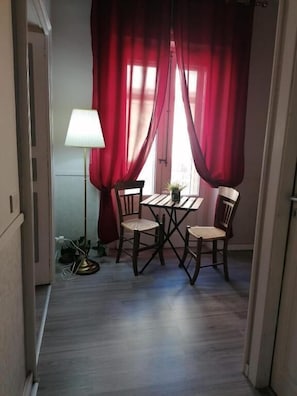 A room with a dining table and chairs, a lamp, and red curtains. - B&Bed 384 Guesthouse  (Enna)