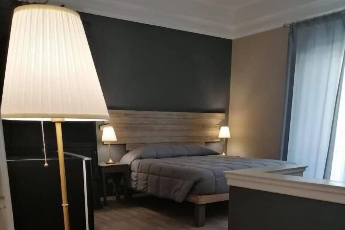 Ein Hotelzimmer mit einem Bett, Nachttischen, einem Schreibtisch, einer Lampe und einer Stehlampe.