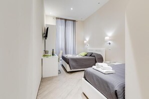 Ett modernt hotellrum med en säng, ett nattduksbord och ett skrivbord med en stol.