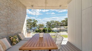 Um deck de madeira com um banco e cadeiras, um muro de pedra e vista para casas e árvores.