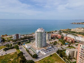 A high-rise hotel with a central courtyard, surrounded by a coastal cityscape. - [Algarve] - T1 Três Castelos (Portimão)
