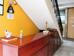 A reception desk with a clock, a Paytm sign, a reception sign, a phone, and a spray bottle. - Hotel Green Gwalior (Gwalior)