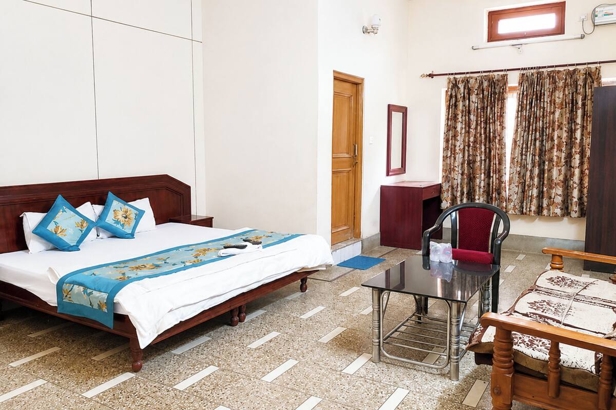 A hotel room with a bed, a desk, a chair, a mirror, and a window with curtains.