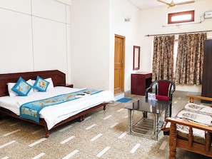 A hotel room with a bed, a desk, a chair, a mirror, and a window with curtains. - Hotel Green Gwalior (Gwalior)
