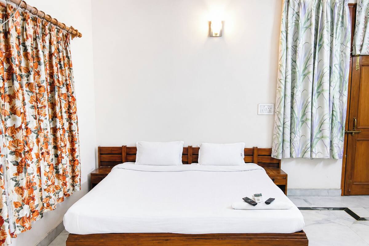 A bed with white bedding, wooden headboard, and two pillows.
