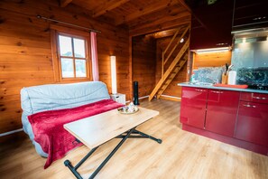 Ein Holzhütten-Interieur mit einem Bett, einem Tisch, einer Küchenzeile und einer Treppe.