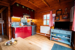 Ein Interieur einer Holzhütte mit Küche, Essbereich und Fernseher.