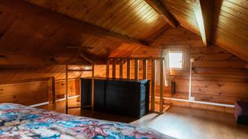 A wooden cabin room with a bed, a dresser, and a window.