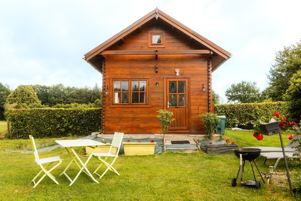 A wooden cabin with a front door, windows, and a small porch area.