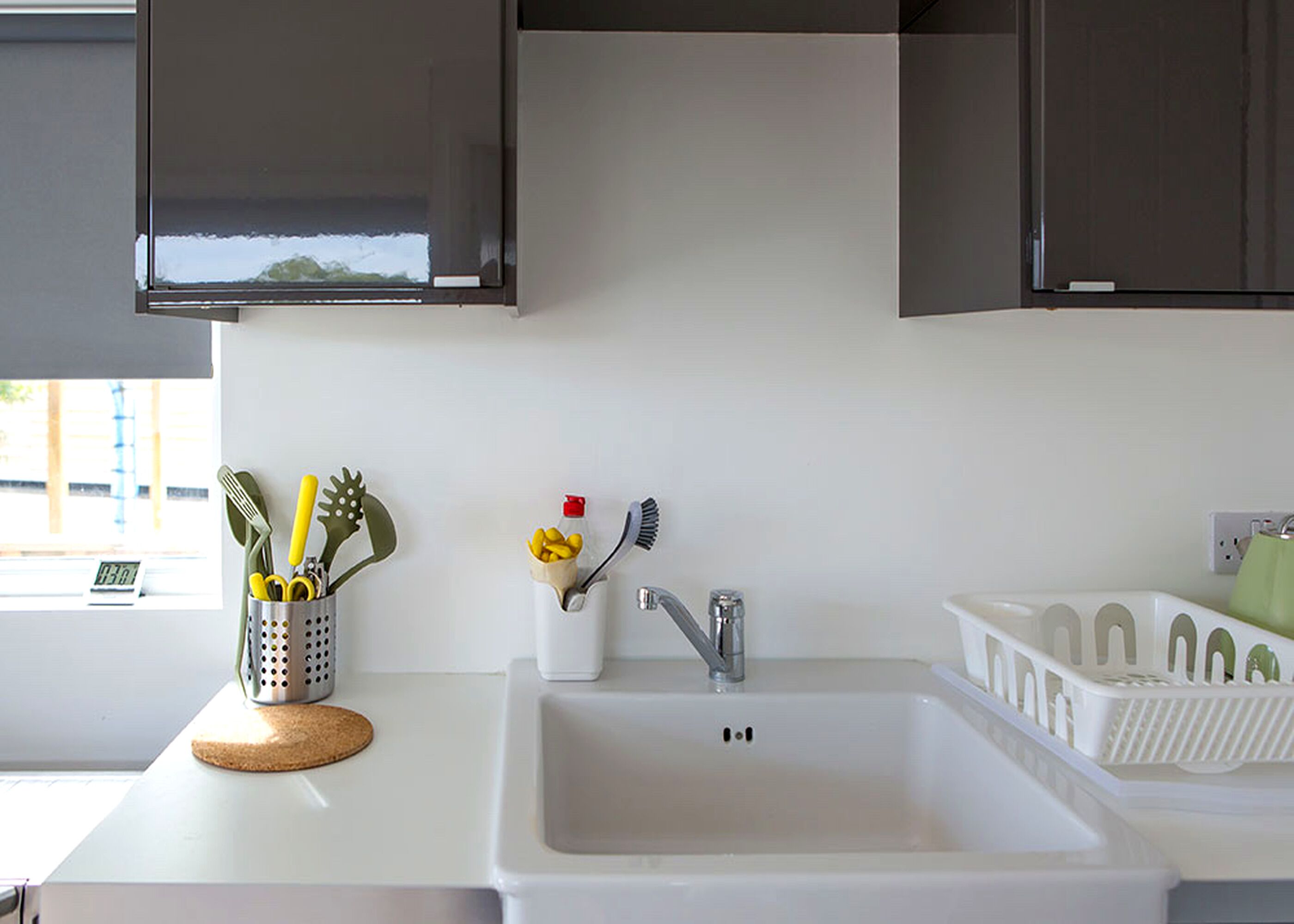 A kitchen with a white sink, stainless steel faucet, and dark cabinets.