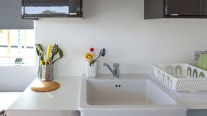 A kitchen with a white sink, stainless steel faucet, and dark cabinets. - Rural cabin for 2 with hot tub (Whitchurch Canonicorum)