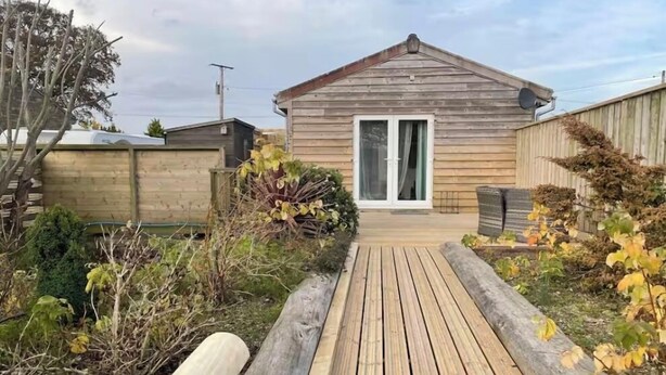 A wooden deck leading to a house with a sliding glass door. - Rural cabin for 2 with hot tub (Whitchurch Canonicorum)