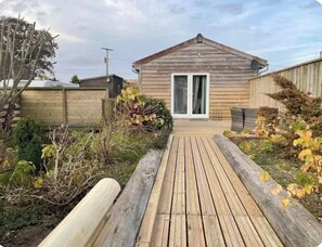 A wooden deck leading to a house with a sliding glass door.