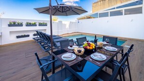 A rooftop dining area with a pool, outdoor seating, and a view of the city. - Dar Sara Holiday Gozitan Home (Victoria)