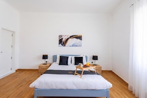 A modern bedroom with a bed, bedside tables, and a painting on the wall. - Dar Sara Holiday Gozitan Home (Victoria)