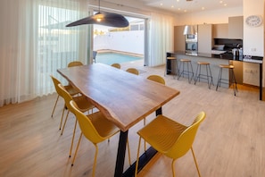 Et moderne køkken med spiseplads, en pool og udsigt til naturen.