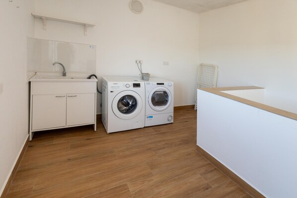 A laundry area with a sink, two washing machines, and a cabinet. - Dar Sara Holiday Gozitan Home (Victoria)